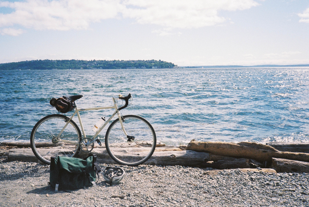 Auf dem Bild ist ein Fahrrad und eine Tasche am Strand zu sehen