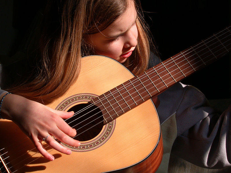 Mädchen zupft auf einer Gitarre