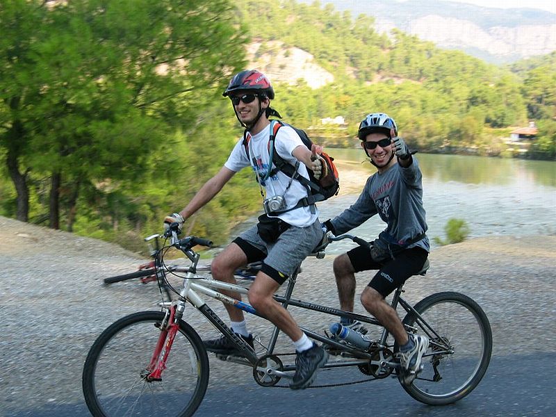 Auf dem Bild sind zwei Radfahrer auf einem Tandem zu sehen