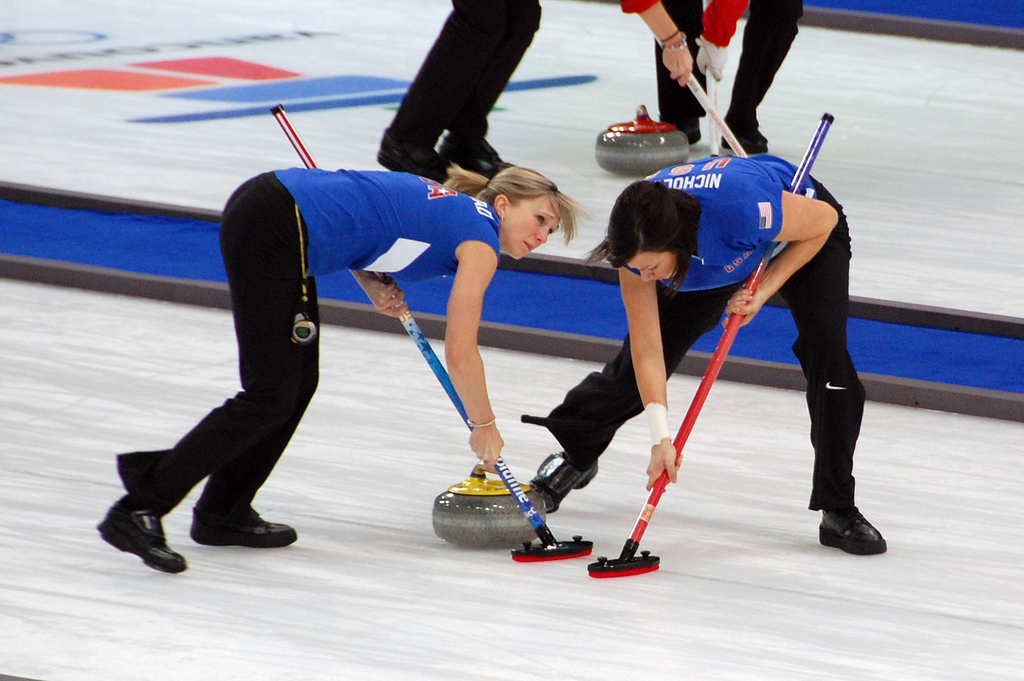 Auf dem Bild sind Curling-Spieler beim wischen zu sehen